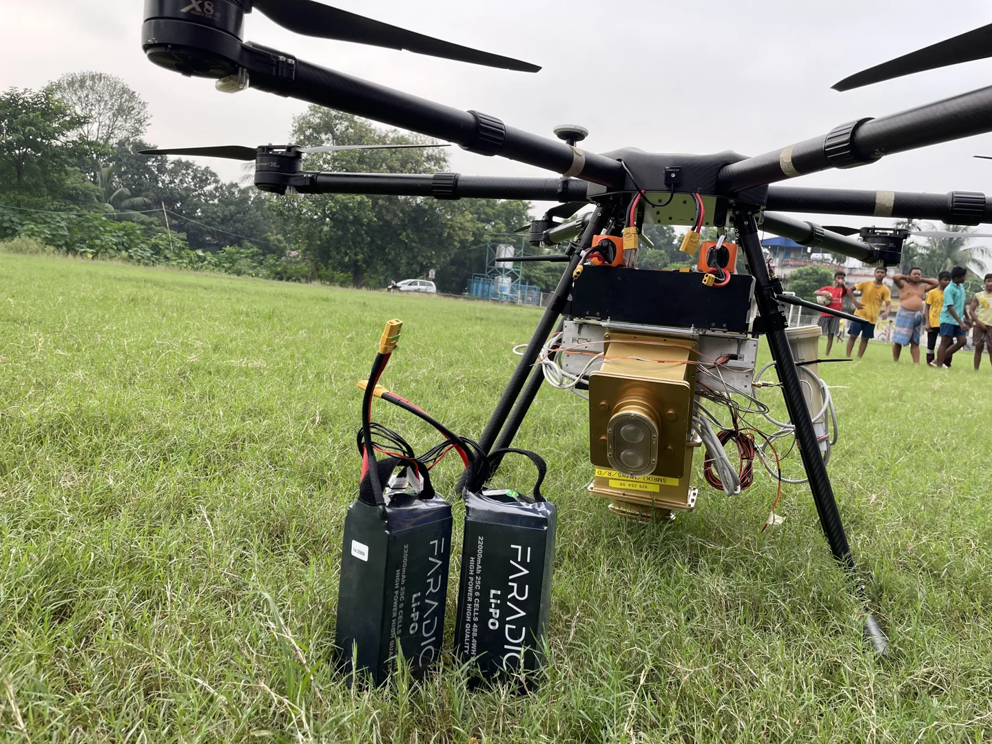 Faradic drone batteries beside a camera-equipped UAV in the field