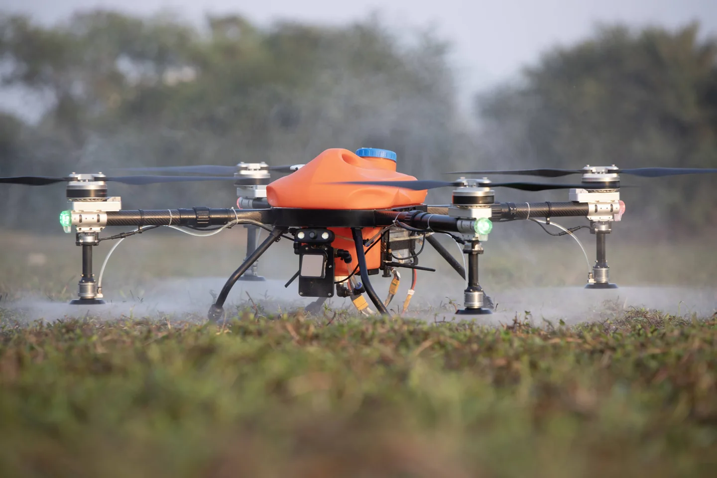 Orange agriculture drone operating close to the ground in a field